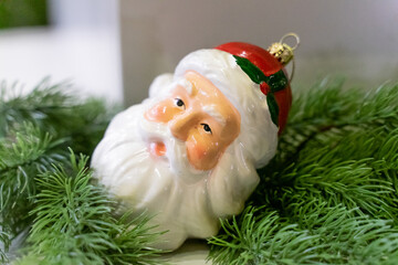 A charming Christmas setup featuring a Santa Claus figurine surrounded by small festive decorations and wrapped presents. The scene highlights warm holiday cheer with miniature ornaments, gift boxes, 