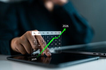 Digital calendar with hand pointing to late December 2025, transition to 2026 with green upward arrow. Business growth, planning, New Year goals and future success. Businesswoman touching tablet.