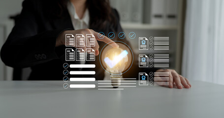 A business professional engages with virtual data displayed above a lightbulb, symbolizing innovation and creativity in a modern office environment. Gantry