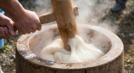 蒸した餅を杵でつく手元のクローズアップ