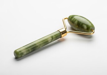Green stone facial massage tool rests on a clean white surface with soft illumination