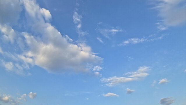 A pale blue sky with light gray and white clouds scattered across it, suggesting an overcast or lightly cloudy day. background style.