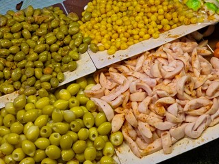 Various preserved and pickled fruits or snacks is displayed in white trays