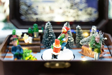 A beautifully crafted Christmas music box featuring reindeer, Santa figures, festive dolls, and a rotating carousel. The intricate design, warm lighting, and nostalgic holiday motifs create a magical 