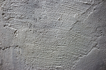 Rough white painted wall texture with strong shadows creating depth and rugged surface patterns