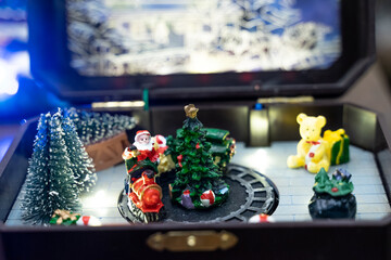 A beautifully crafted Christmas music box featuring reindeer, Santa figures, festive dolls, and a rotating carousel. The intricate design, warm lighting, and nostalgic holiday motifs create a magical 