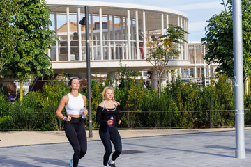 Healthy women running in a bright park wearing athletic gear and enjoying outdoor fitness on a calm sunny day