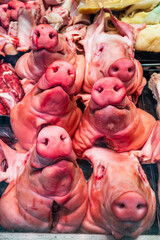 Freshly displayed pork cuts at a bustling market showcasing various meat parts and offal, attracting shoppers on a lively afternoon