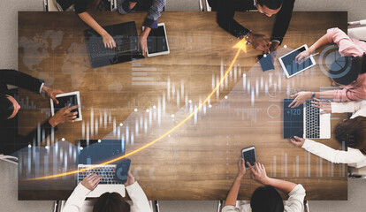 Aerial view of a dynamic business meeting where professionals analyze data trends using laptops and tablets, fostering teamwork and growth in a collaborative environment. Scalp