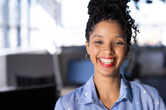 African American woman standing in office with computer monitors and swivel chairs, copy space