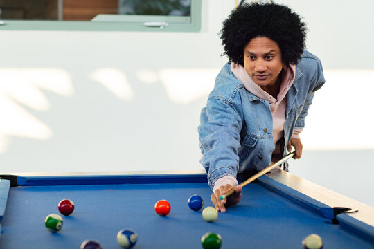 African American man lining up shot on pool table using cue in game room, copy space