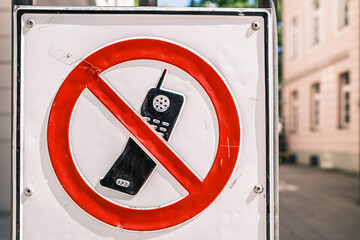 Sign prohibiting mobile phone use in public area during daytime, alerting visitors to stay focused on their surroundings