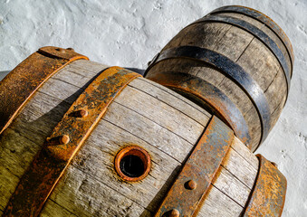 Old wooden barrels stacked against a stone wall in a historic cellar creating an atmosphere of tradition and time-honored craftsmanship