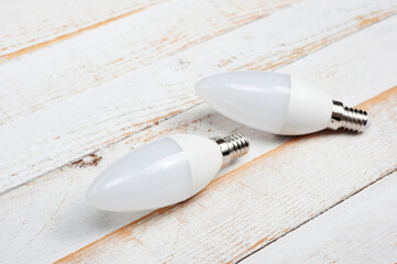 Two LED lamps with E14 sockets lying on a wooden surface.