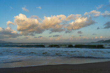 Obraz premium Beautiful sunset over the ocean with dramatic clouds and wave.