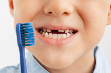 Close-up view of a child's mouth showing a missing baby tooth and a blue toothbrush.