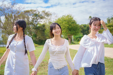 Girls walking and talking outdoors, laughing and enjoying a bright sunny day together, expressing friendship, joy, and a carefree youth lifestyle.