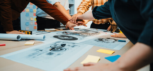 A diverse group of professionals engaged in a collaborative meeting, focusing on project blueprints and ideas, demonstrating teamwork and creativity in a modern office space. SACTR