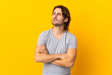 Fototapeta premium Young handsome man isolated on yellow background looking to the side
