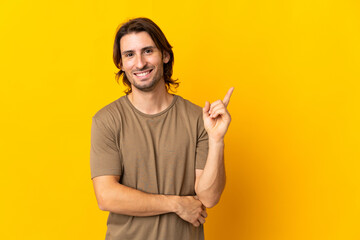 Fototapeta premium Young handsome man isolated on yellow background happy and pointing up