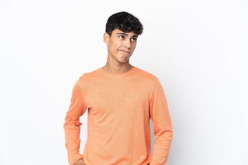 Fototapeta premium Young man over isolated white background having doubts while looking up