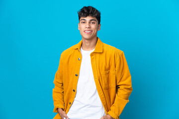 Young man over isolated blue background laughing