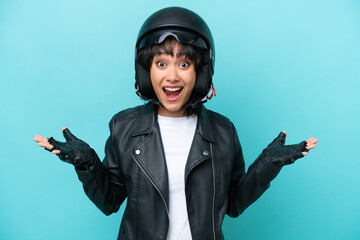 Young Argentinian woman with a motorcycle helmet isolated on blue background with shocked facial expression