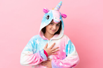 Little caucasian woman wearing a unicorn pajama isolated on pink background smiling a lot