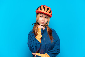 Young cyclist girl isolated on blue background and looking up