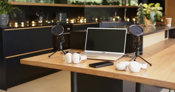 At start camera is panning left across wooden table revealing audio recording setup and leafy plant