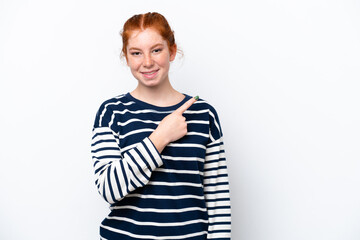 Young reddish woman isolated on white background pointing to the side to present a product