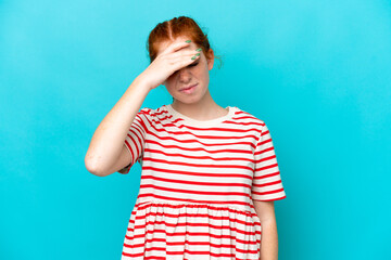 Young reddish woman isolated on blue background with headache
