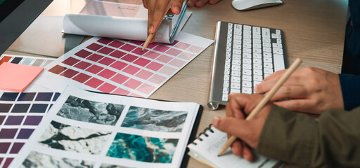 Two designers collaborate over color palettes, sketches, and digital tools, showcasing a creative workspace filled with inspiration for art and design projects. SACTR