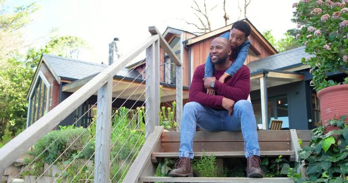 African American father and son hugging to bond after son climbing wooden front porch steps
