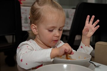 Little girl sitting at the table and eating soup