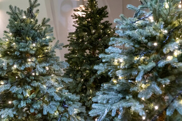 A festive Christmas tree display featuring sparkling ornaments, twinkling lights, and seasonal decorations. The tree is adorned with baubles, ribbons, garlands, and a bright star on top, creating a wa