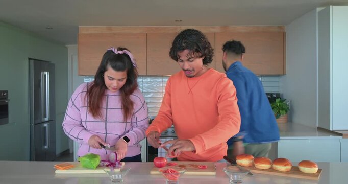 Diverse friends chopping veggies, preheating stove and oiling pans in kitchen for steak searing