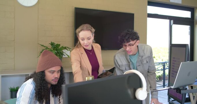 Diverse coworkers working in office, reviewing tablet and updating computer displays for project