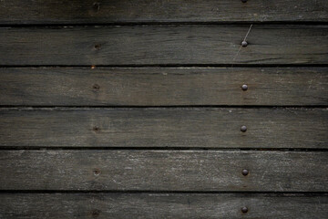Fototapeta premium Dark Wooden Background. Close-up of dark wooden planks arranged horizontally with visible grain and small nails, creating a rustic texture and natural pattern for background or design use