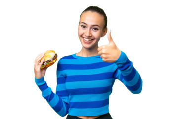 Young Arab woman holding a burger over isolated background with thumbs up because something good has happened