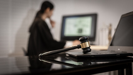 A focused Asian female judge works on complex cases involving cyber law, data protection, and digital rights, with the gavel and laptop symbolizing modern legal authority.