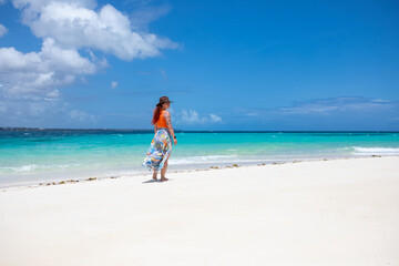 Obraz premium Beautiful girl with red hair on the beach. Sunny day. Colorful sky. Sandy beach.