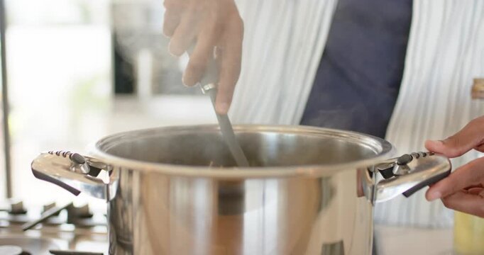 As gas burner is lighting, cook is stirring pot then is scooping spaghetti noodles for serving