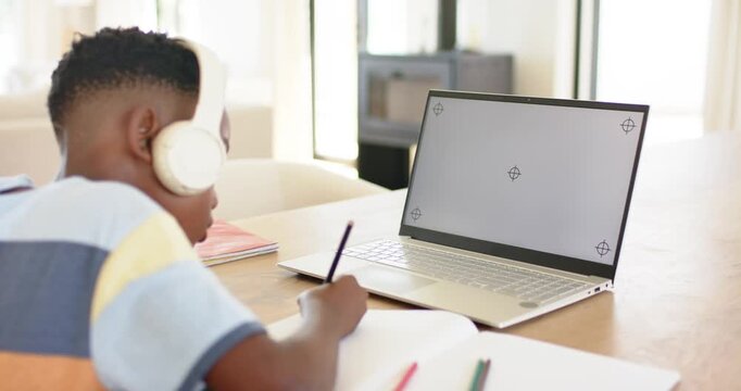 At lesson start lifting pencil, student writing notes, glancing at laptop to follow online lesson