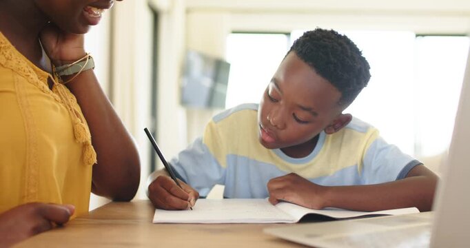 African American mother at home encouraging son writing in notebook, son high-fiving, writing again