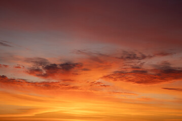 Obraz premium Evening sky painted with vibrant golden-hour clouds in orange, red and purple hues, a tranquil, scenic cloudscape at dusk capturing warm, serene atmospheric light