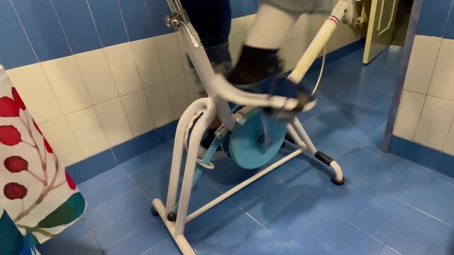 P&icirc;ernas pedaleando de hombre con rodilla operada en bicicleta est&aacute;tica antigua en rehabilitaci&oacute;n 