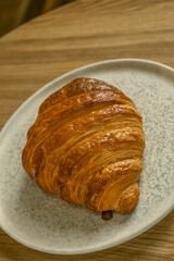 Close-up of a golden brown butter croissant served on a ceramic plate.