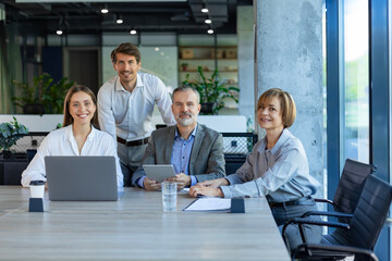 Group of positive successful modern people sitting in office and looking at camera.