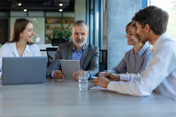 Successful businesspeople working in a coworking space working with laptop discussing strategy and business plan in modern office.